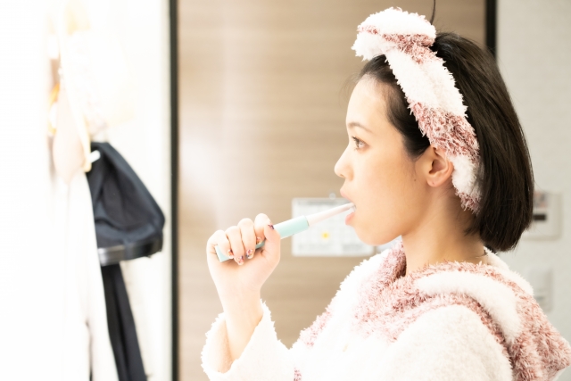 洗面所で歯磨きをしている女性のイメージ写真