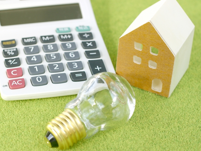 電卓と電球の写真で電気料金の計算や節約をイメージした画像