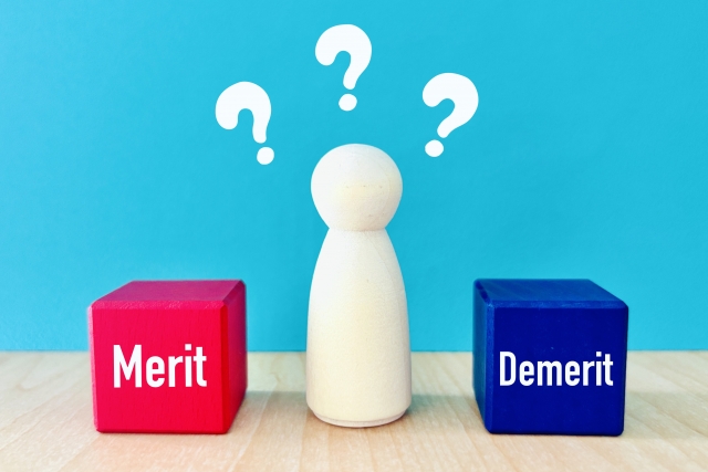 青い背景に「Merit」と「Demerit」の文字が並び、中央に白い駒のオブジェが立っているイメージ