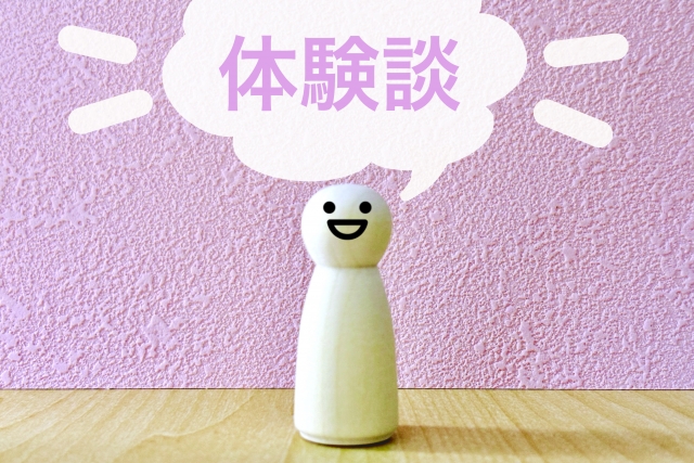 白い人型のオブジェが笑顔で立っており、背景に「体験談」と書かれたピンク色のボードが配置されているイメージ画像。