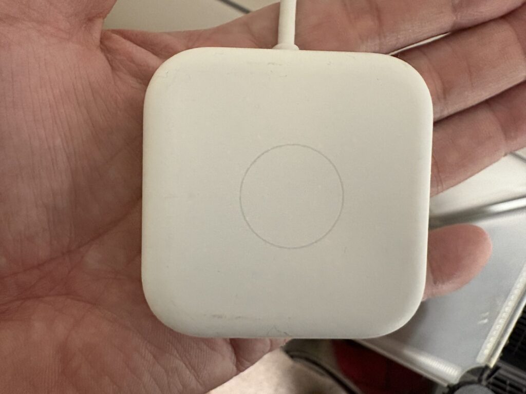 手に持った白いスマートリモコンの写真