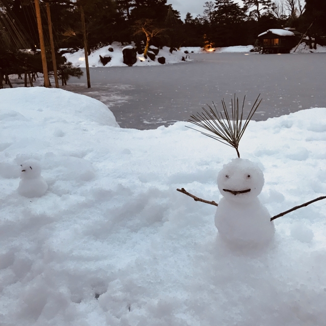 雪の中に作られた雪だるまと、その奥に広がる冬の景色