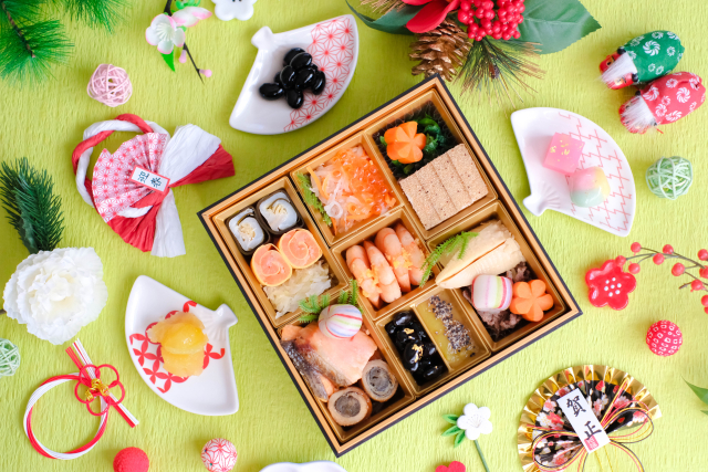 色とりどりの料理が詰められたおせち料理のお重。海老、かまぼこ、煮物、デザート風の品まで豪華に盛り付けられている。