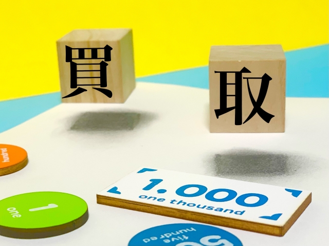 「買取」の文字ブロックと1,000円札をイメージしたパネルが並ぶ写真。買取サービスや現金化をイメージしたビジュアル。